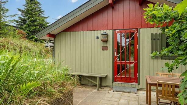 A small building with a red door and a number '27' sign, surrounded by greenery. - "Nikoletta" - 150m from the sea by Interhome (Fjerritslev)