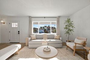 A modern living room with a sofa, a round coffee table, a chair, a lamp, and a potted plant. - Stay SanDi - Resort Style Paradise | Pool Hot Tub, Renovated, AC (San Diego)