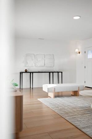 Ett minimalistiskt vardagsrum med en bänk, ett bord och en matta.