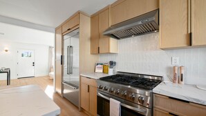 Eine moderne Küche mit Edelstahlgeräten, Holzschränken und einer weißen Arbeitsplatte.