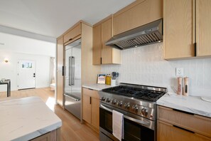 Eine moderne Küche mit Edelstahlgeräten, Holzschränken und einer weißen Arbeitsplatte.