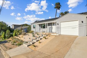 Ein modernes, zweistöckiges Haus mit Garage, ein Veranda und einem angelegten Vorgarten.