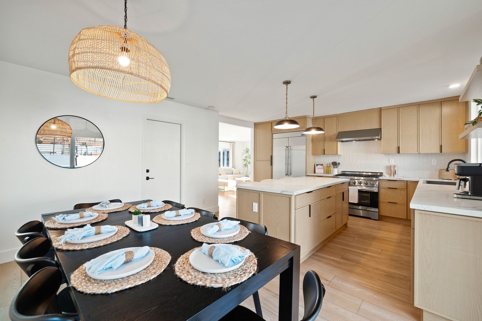 A modern kitchen with wooden cabinets, a central island, and a dining area set for six.