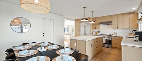 A modern kitchen with wooden cabinets, a central island, and a dining area set for six.