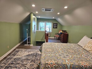 Une chambre à coucher avec un grand lit, une commode, une chaise et une fenêtre avec des rideaux.