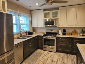 A modern kitchen with stainless steel appliances, white cabinets, and a granite countertop. - Newly remodeled 3BR/2BA home with a huge back porch on a quiet street (Altavista)