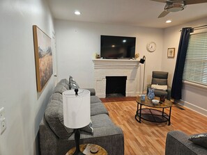 A living room with a fireplace, a sofa, a television, and a coffee table. - Newly remodeled 3BR/2BA home with a huge back porch on a quiet street (Altavista)