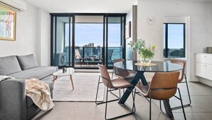 Uma sala de estar moderna com um sofá, uma mesa de centro e um espaço de refeições com cadeiras e uma mesa de vidro.
