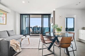 Ein modernes Wohnzimmer mit Sofa, Couchtisch und Essbereich mit Stühlen und einem Glastisch.