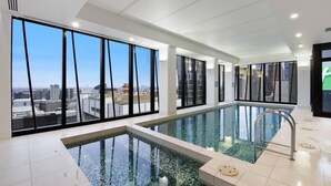 En moderne indendørs swimmingpool med store vinduer og udsigt over byen.