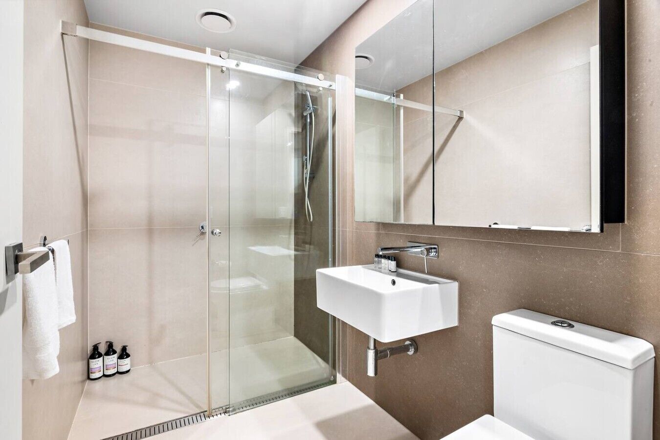 Un bagno moderno con cabina doccia in vetro, lavandino bianco e un water.