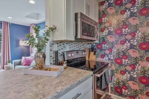 A kitchen with a microwave, stove, and a decorative backsplash. - The Swiftie: Sleeps 5, Pool, City & River Views, Near Broadway (Nashville)