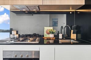 Eine moderne Küche mit einem Gasherd, einem Slow Cooker und einem Waschbecken mit einem schwarzen Wasserhahn.