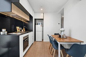 Une cuisine moderne avec une table et des chaises en bois, un réfrigérateur et un four encastré.