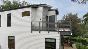 Et moderne hus med to etager, en altan, store vinduer og en garage.