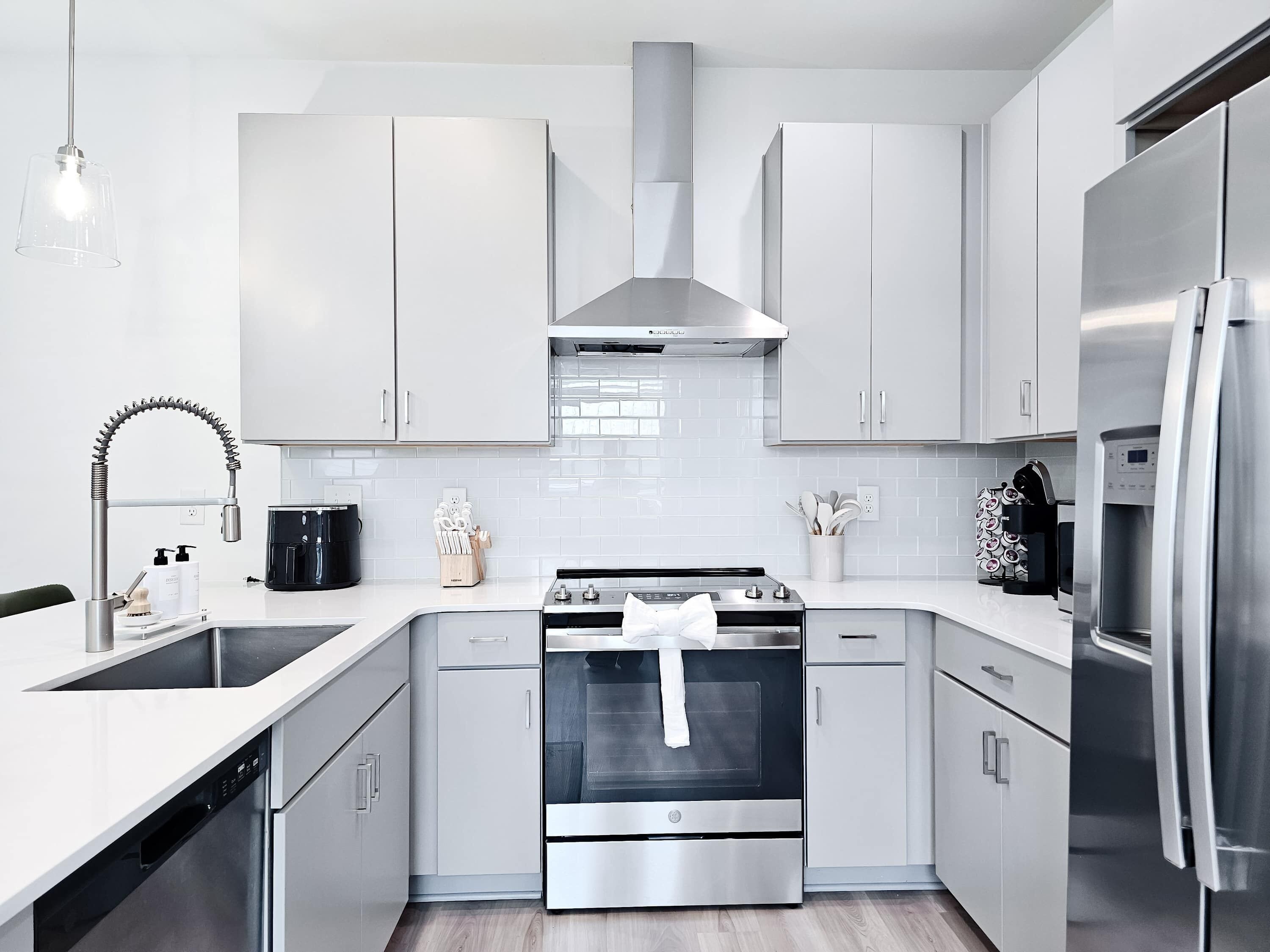 A modern kitchen with stainless steel appliances, white cabinetry, and a built-in oven.