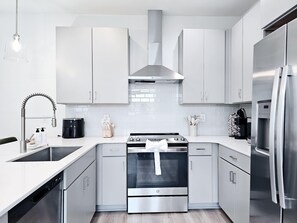 Eine moderne Küche mit Edelstahlgeräten, weißen Schränken und einem eingebauten Backofen.