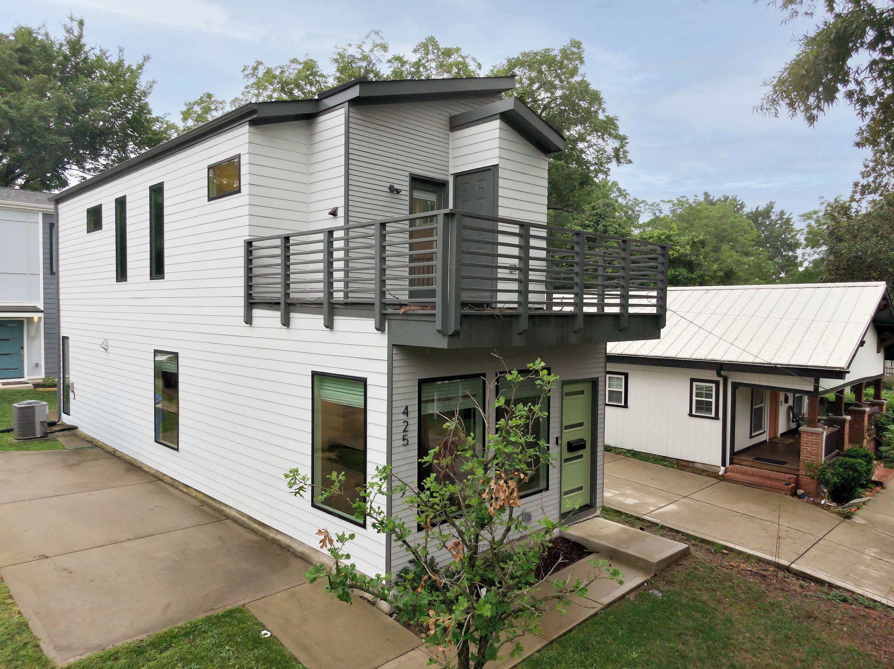 A modern two-story house with a balcony, large windows, and a visible number '425'.