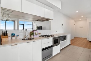 Eine moderne Küche mit weißen Schränken, Edelstahlgeräten und einem großen Fenster für natürliches Licht.