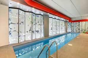 Ein Hallenbad mit Glaswand, roter Decke und Fliesenboden.