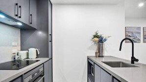 Uma cozinha moderna com forno embutido, pia de aço inoxidável e um vaso com flores na bancada.