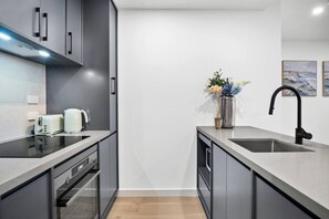 Eine moderne Küche mit Einbauofen, Spüle aus Edelstahl und Blumen in einer Vase auf der Arbeitsplatte.
