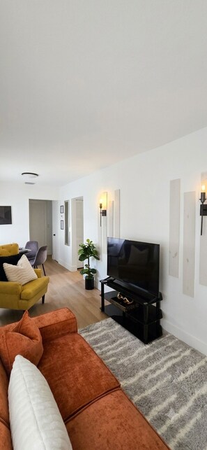 A modern living room with a sofa, TV, and decorative wall lights. - Moderno Apto 2 Hab  Cerca Design District & MIA (MIAMI)