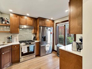 A modern kitchen with wooden cabinets, stainless steel appliances, and a view of the outdoors. - Saltbox 9D - 3BR Quechee retreat (Quechee)
