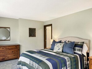 A bedroom with a bed, dresser, mirror, and wall-mounted clock. - Saltbox 9D - 3BR Quechee retreat (Quechee)
