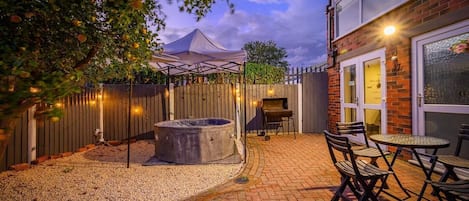 Un espace patio aménagé avec un jacuzzi, un barbecue et des meubles de jardin.