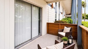 Ein Balkon mit Schiebeglastür, Korbmöbeln und einem Pflanzgefäß mit Kerze.