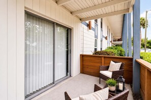 Ein Balkon mit Schiebeglastür, Korbmöbeln und einem Pflanzgefäß mit Kerze.