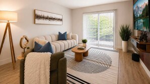 Ein modernes Wohnzimmer mit Sofa, Couchtisch, Lampe und einem Gemälde an der Wand.