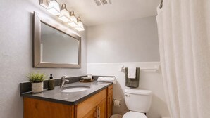 Ein Badezimmer mit Waschtisch, Spüle, Spiegel und Toilette.