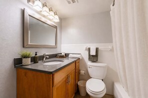 Ein Badezimmer mit Waschtisch, Spüle, Spiegel und Toilette.