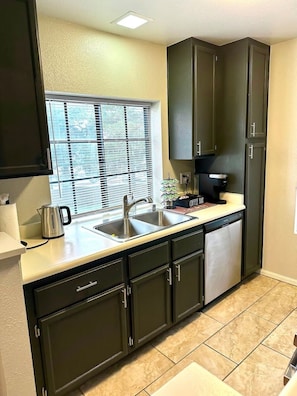 A kitchen with a sink, cabinets, a window with blinds, and a coffee maker. - Modern Pet-Friendly 2BR | Near Strip & Chinatown (Las Vegas)