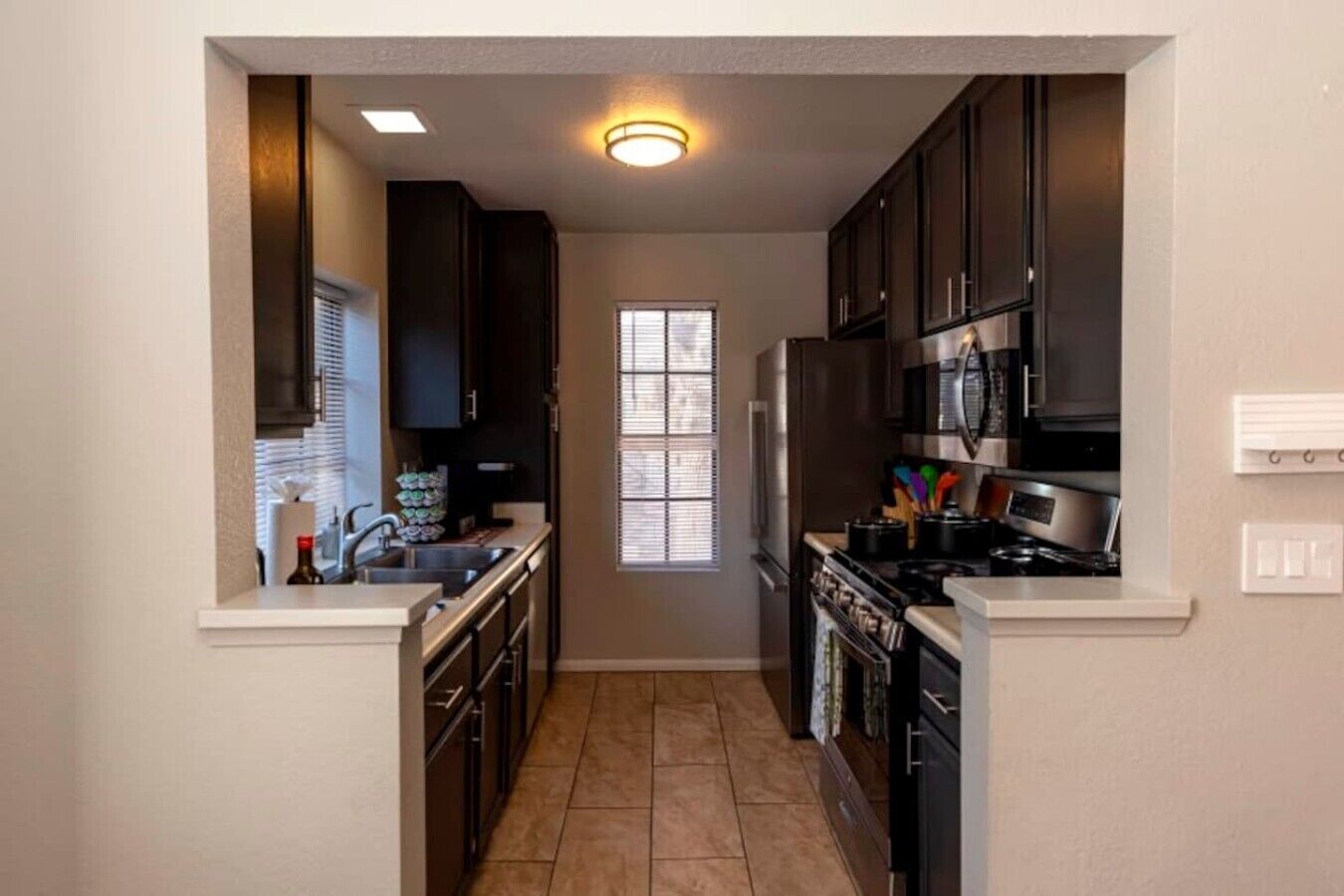 A narrow kitchen with dark cabinets, a window, and a built-in oven.