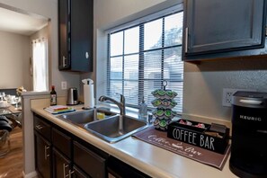 Une cuisine moderne dotée d’un évier à deux bacs, d’un panneau indiquant un espace dédié au café et d’une machine à café Keurig.