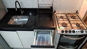 Uma cozinha com pia de aço inoxidável, fogão e forno embutido.