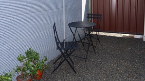En uteplats med ett bord och stolar, krukväxter och ett staket av trä.