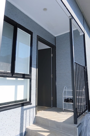 A modern building with a brick facade, a large window, and a metal railing. - New Modern Family Retreat 3BR Near Parramatta (Northmead)