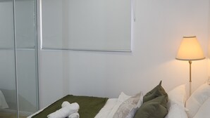 Ett hotellrum med en säng, en sänglampa och en spegel.
