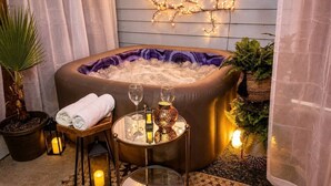 A hot tub with a purple interior, surrounded by plants, candles, and a table with glasses and a lantern. - East Austin, Walkable, Private Hot Tub and Parking (Austin)