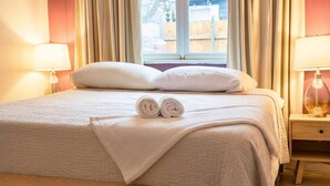 A neatly made bed with pillows, a rolled towel, and a bedside lamp. - East Austin, Walkable, Private Hot Tub and Parking (Austin)