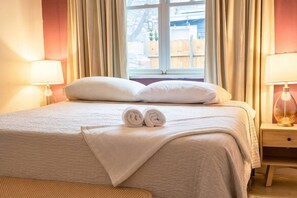 A neatly made bed with pillows, a rolled towel, and a bedside lamp. - East Austin, Walkable, Private Hot Tub and Parking (Austin)