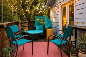 An outdoor seating area with a cushioned bench, chairs, and a table, surrounded by string lights and greenery. - East Austin, Walkable, Private Hot Tub and Parking (Austin)