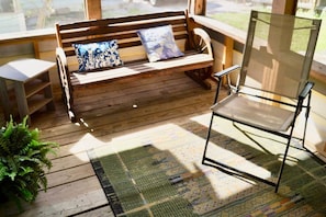 A wooden bench with cushions, a metal chair, and a patterned rug on a wooden deck. - King•Heart of East Downtown•Self Check-In (Austin)