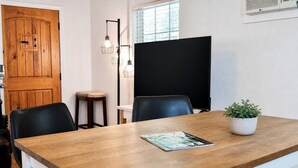 Ett konferensrum med ett träbord, svarta stolar, en krukväxt och en svart skärm på väggen.