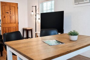 A conference room with a wooden table, black chairs, a potted plant, and a black screen on the wall. - Private Cozy Retreat,1GB Fiber WiFi, Near Downtown (Austin)