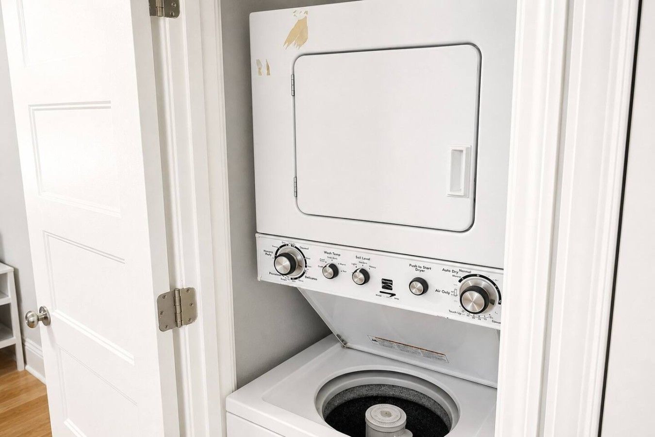 Une machine à laver compacte, de couleur blanche, avec une porte à chargement frontal, des boutons de commande et un petit tambour circulaire visible à l’intérieur.